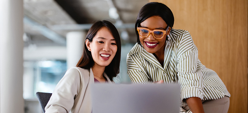 two smiling women looking at a laptop screen